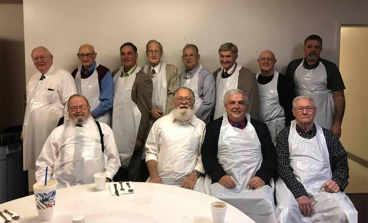 Men of the church wearing plastic aprons after cooking breakfast for the ladies.